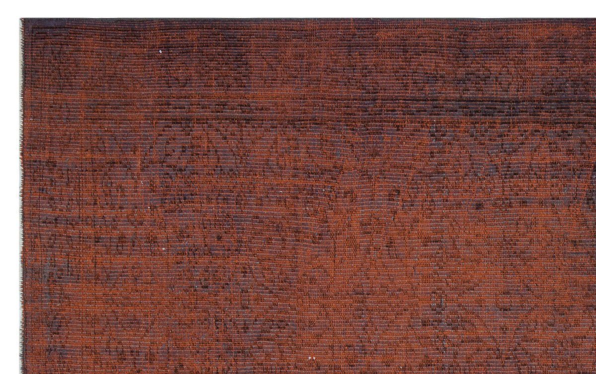 Rust-colored rug with a dark, distressed traditional floral pattern and visible horizontal weave texture.