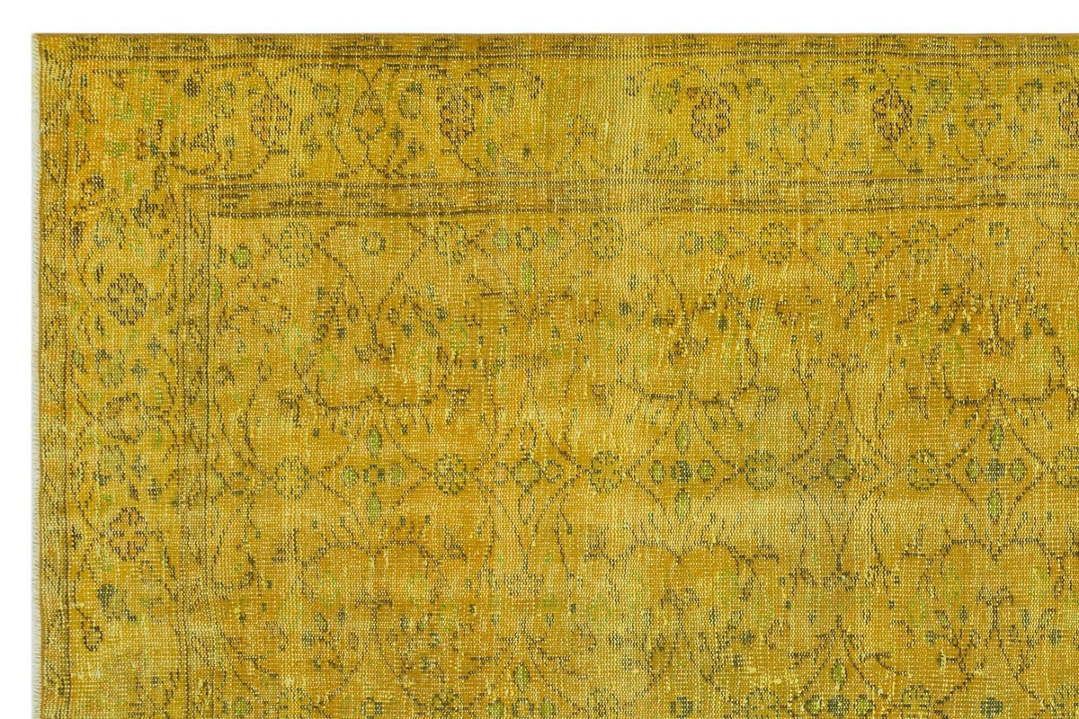 Mustard yellow vintage-style rug with a distressed floral medallion pattern and a detailed border.