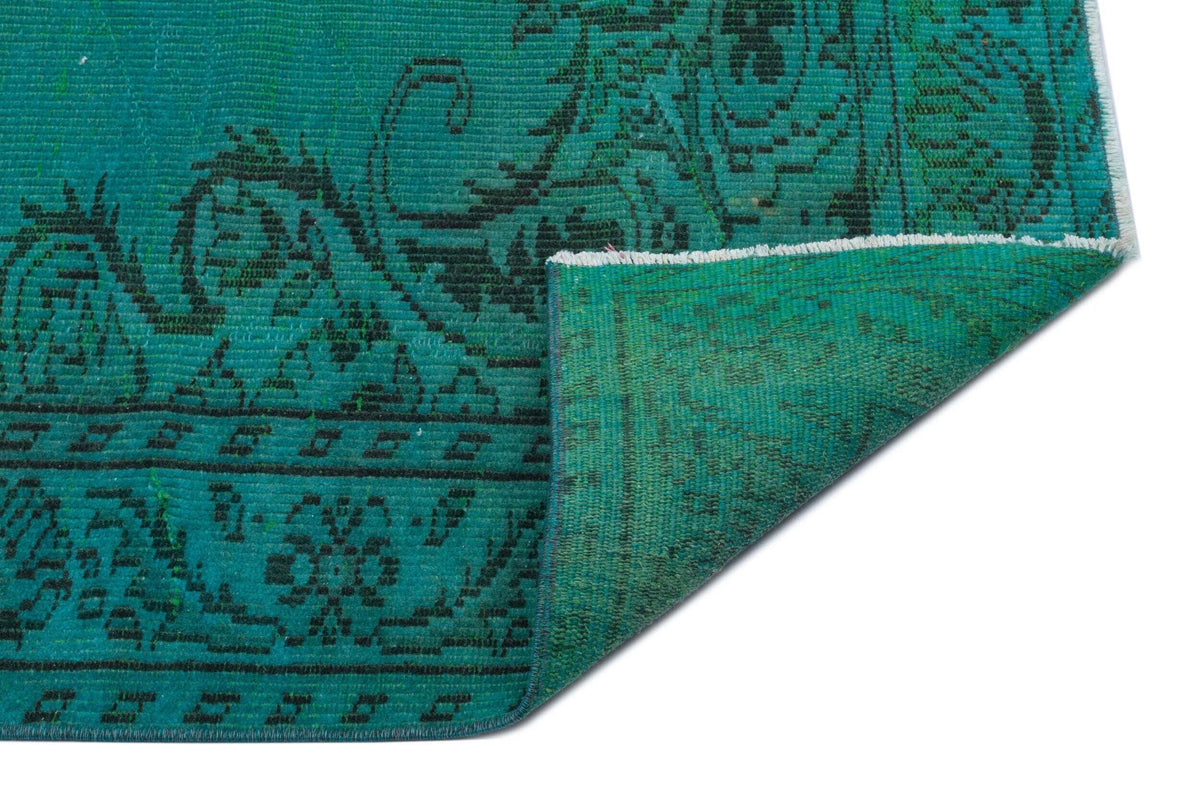 Teal and black rug with a traditional floral medallion pattern, shown with a corner folded over on a white background.