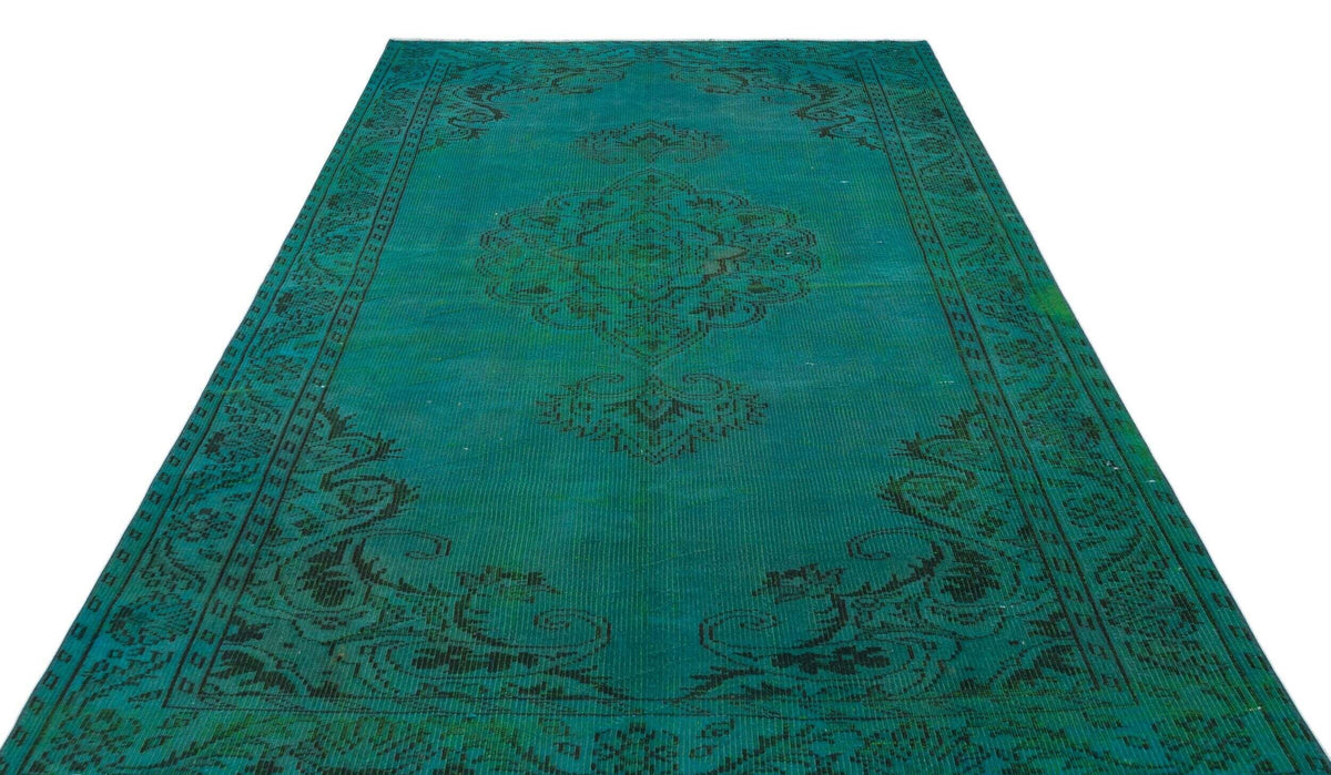 Teal rug with a distressed black traditional medallion pattern and ornate border on a white background.