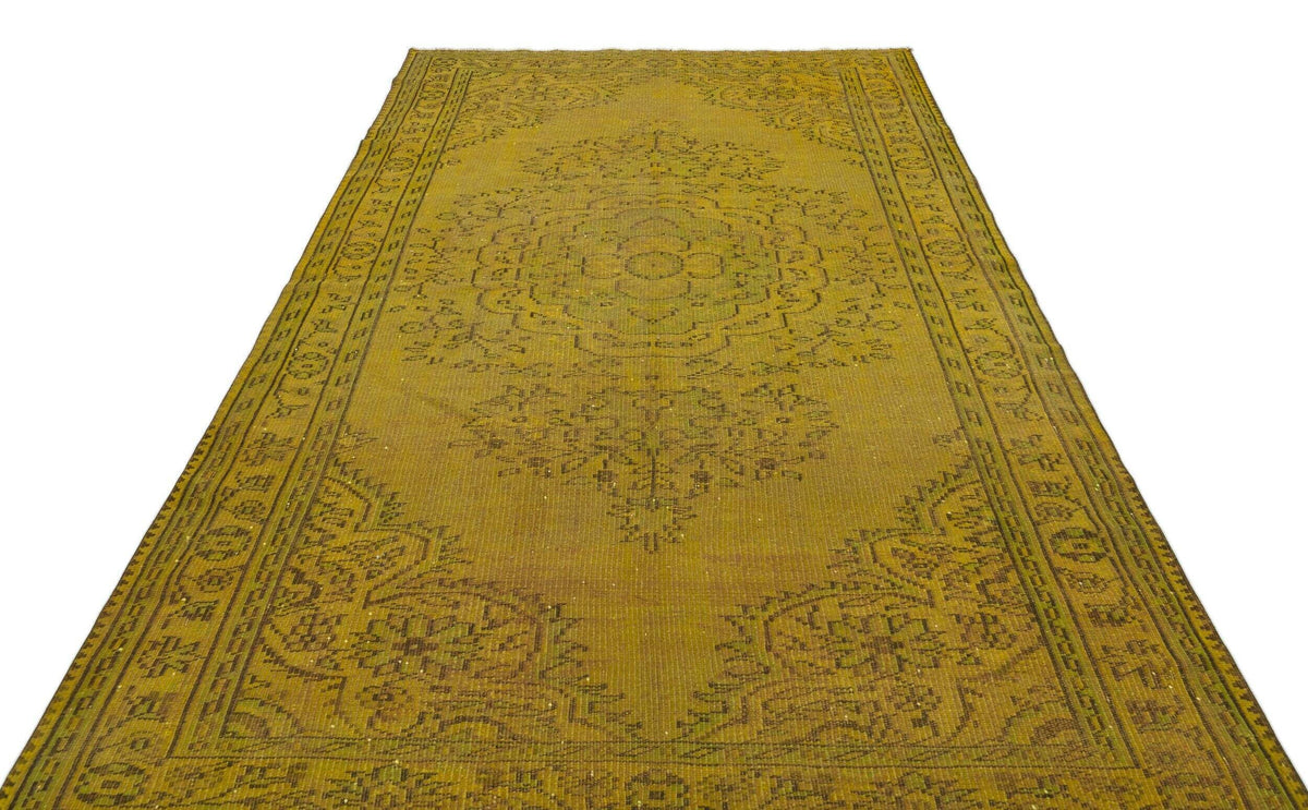 Olive green vintage-style rug with a central floral medallion and intricate border pattern on a white background.