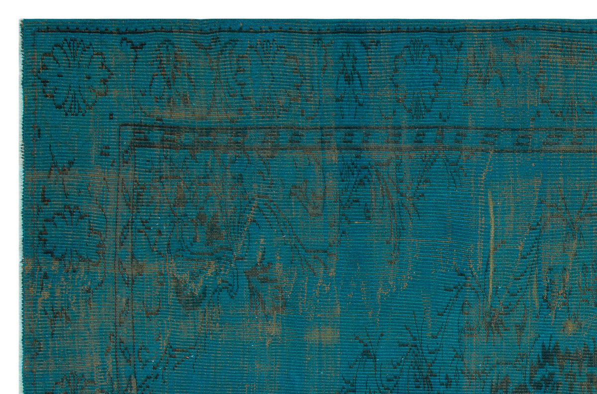 Teal and dark brown distressed rug with a traditional floral medallion border and intricate vine pattern.