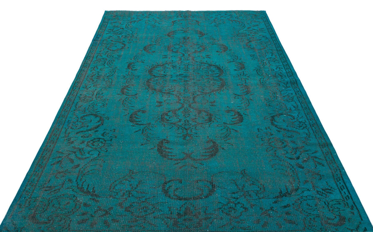 Teal rug with a distressed black traditional floral medallion pattern on a white background.
