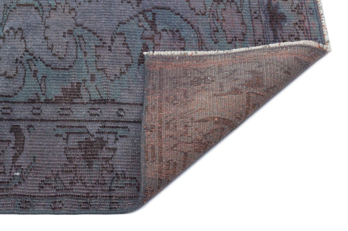 Load image 1 in gallery view. Blue and grey vintage-style rug with a floral medallion pattern, shown with a corner folded to reveal the brown backing.