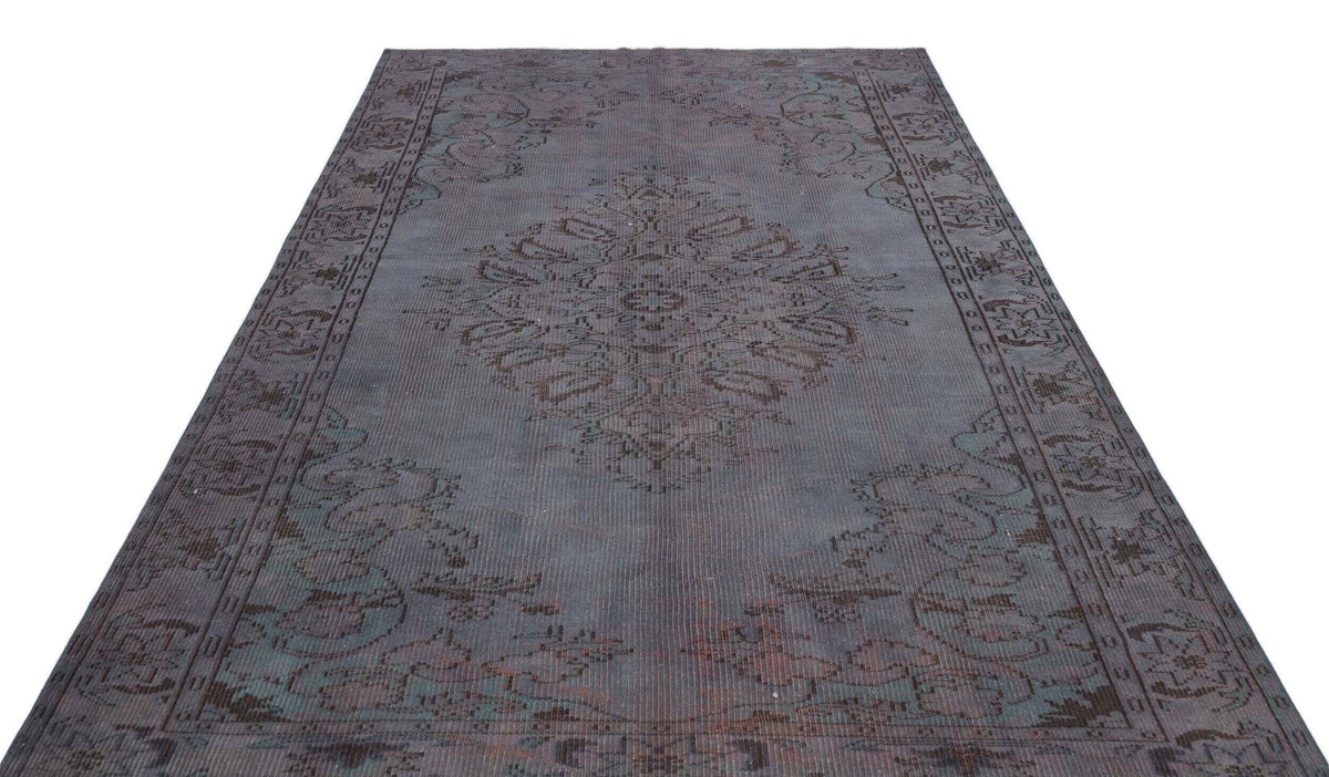 Charcoal and slate blue distressed rug with a central medallion and ornate border pattern on a white background.
