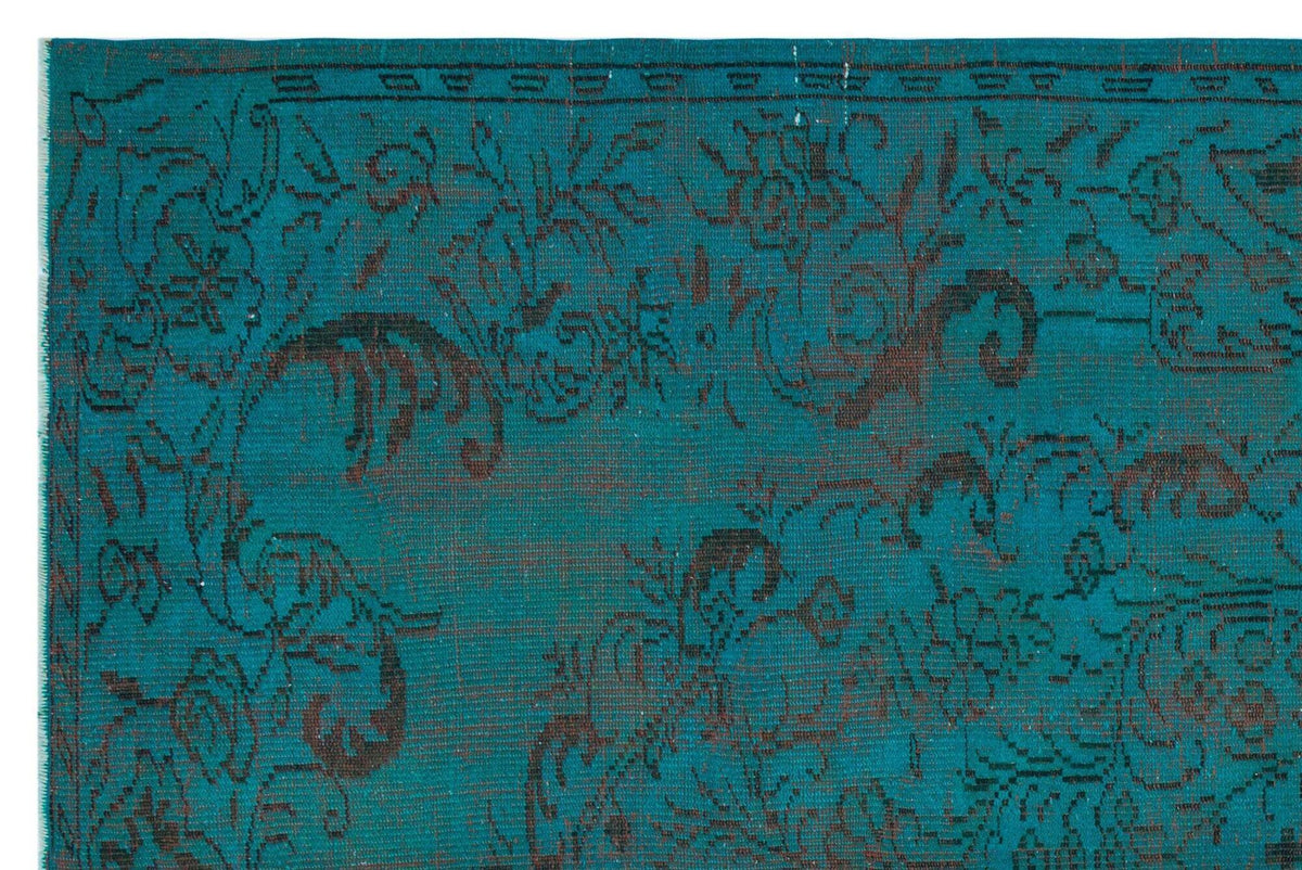 Teal rug with a dark brown distressed floral pattern and a linear border.