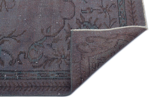 Load image 1 in gallery view. Charcoal and teal distressed traditional rug with a floral pattern, shown with a corner folded over on a white background.