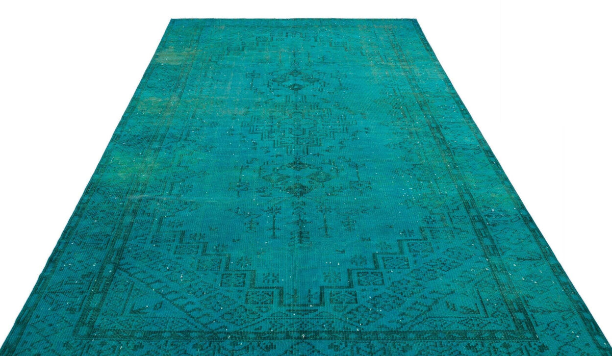 Teal vintage-style rug with a distressed central medallion and geometric border pattern on a white background.