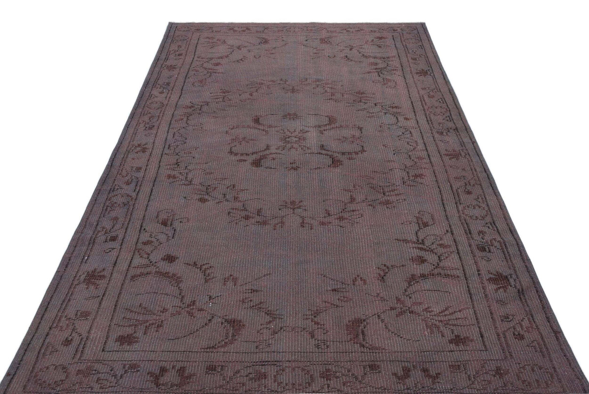 Dark brown rectangular rug with a subtle, tonal floral medallion pattern and a decorative border on a white background.