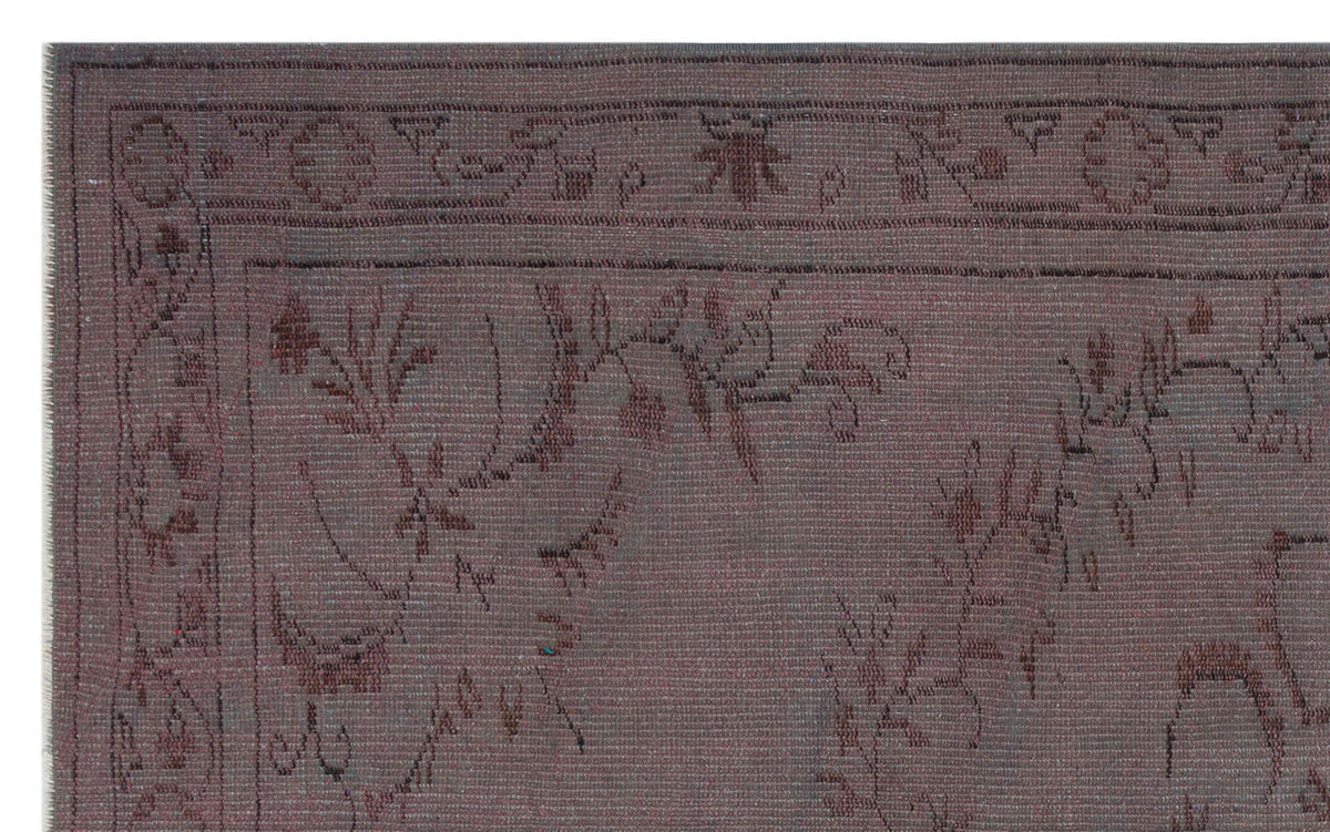Dark charcoal rug with a subtle, tonal floral vine pattern and a decorative geometric border.