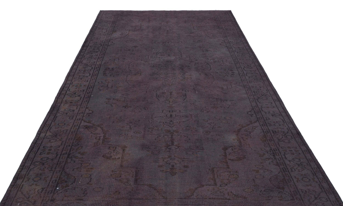 Dark charcoal overdyed vintage rug with a faint, traditional Persian-style medallion pattern on a white background.