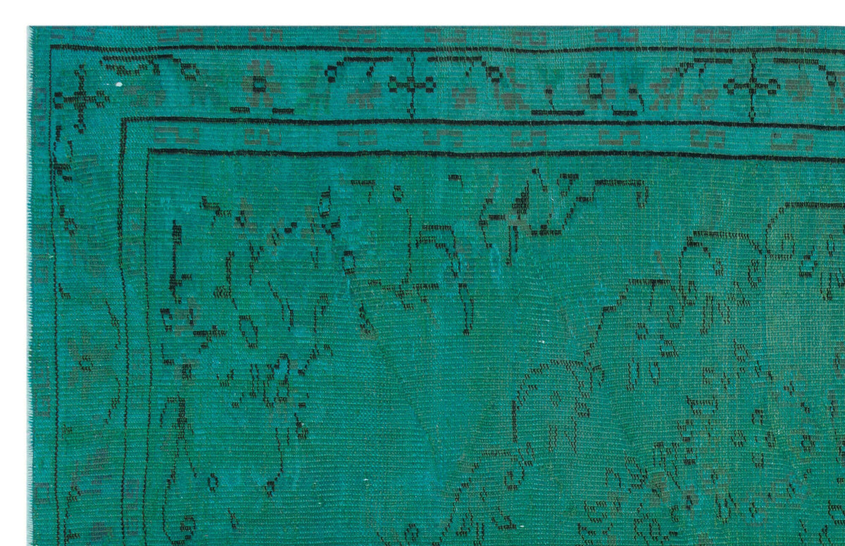 Teal rug with a distressed black geometric border and faded traditional medallion pattern.