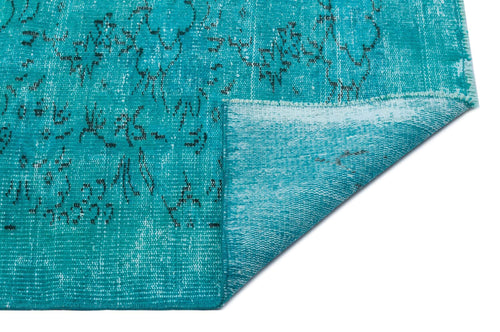 Load image 1 in gallery view. Turquoise distressed rug with a faded black floral pattern, shown with a folded corner on a white background.