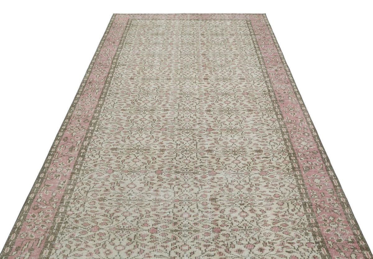 Cream and pink vintage-style rug with a distressed floral medallion pattern and a wide decorative border.
