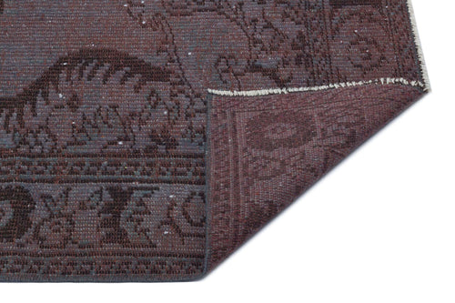 Load image 1 in gallery view. Deep plum and charcoal distressed rug with a traditional medallion pattern, shown with a corner folded over.