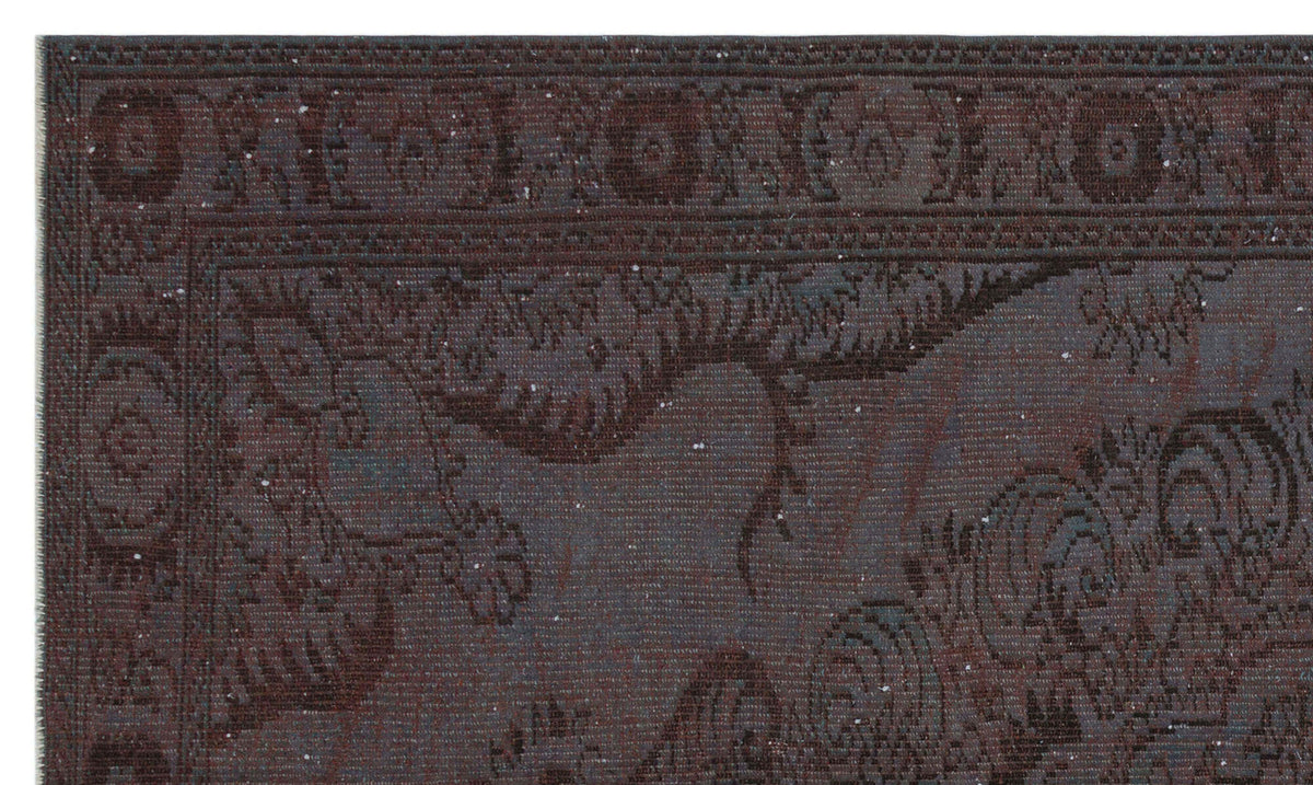 Dark charcoal and brown traditional rug with a distressed, faded floral medallion pattern and a detailed border.