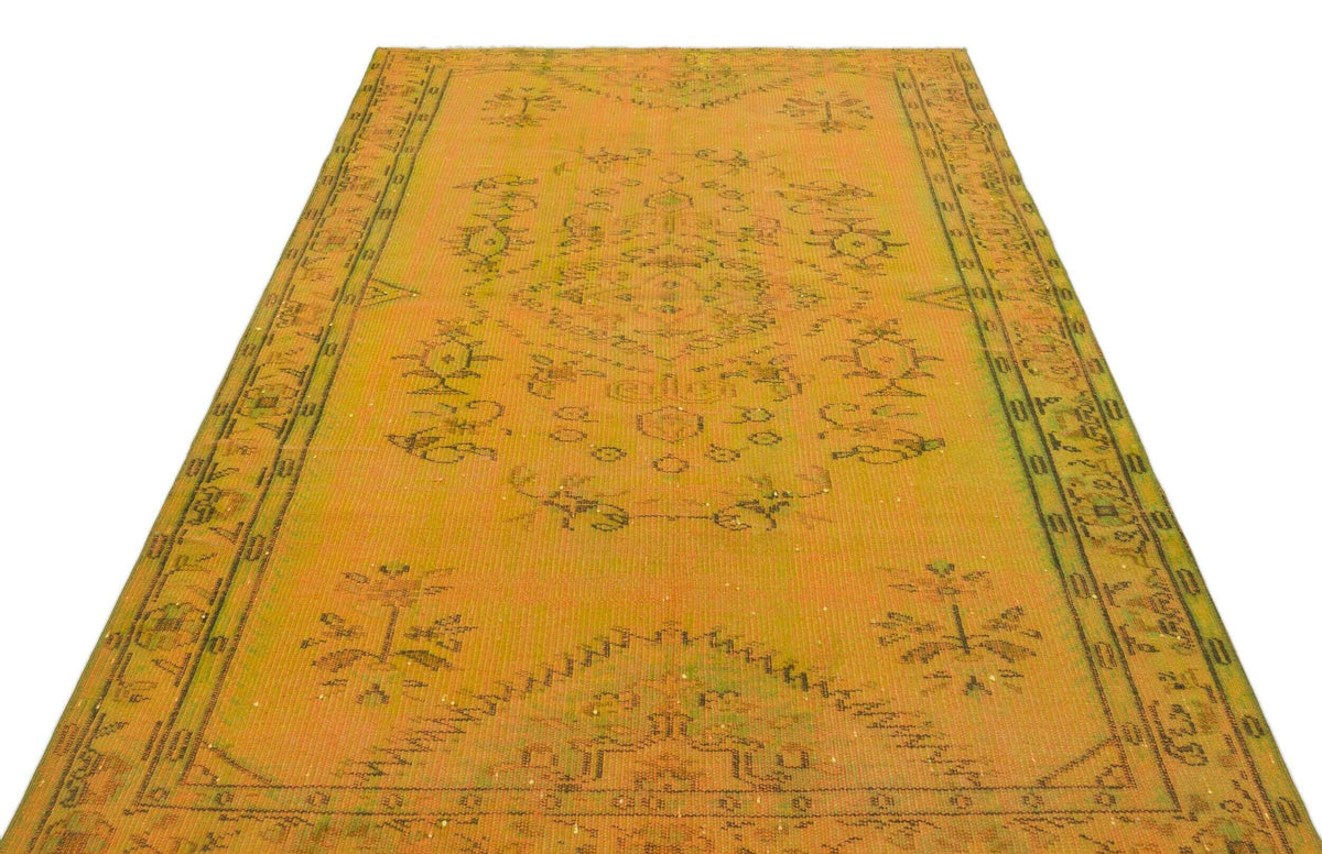 Mustard yellow vintage rug with a dark green central medallion and geometric border pattern on a white background.