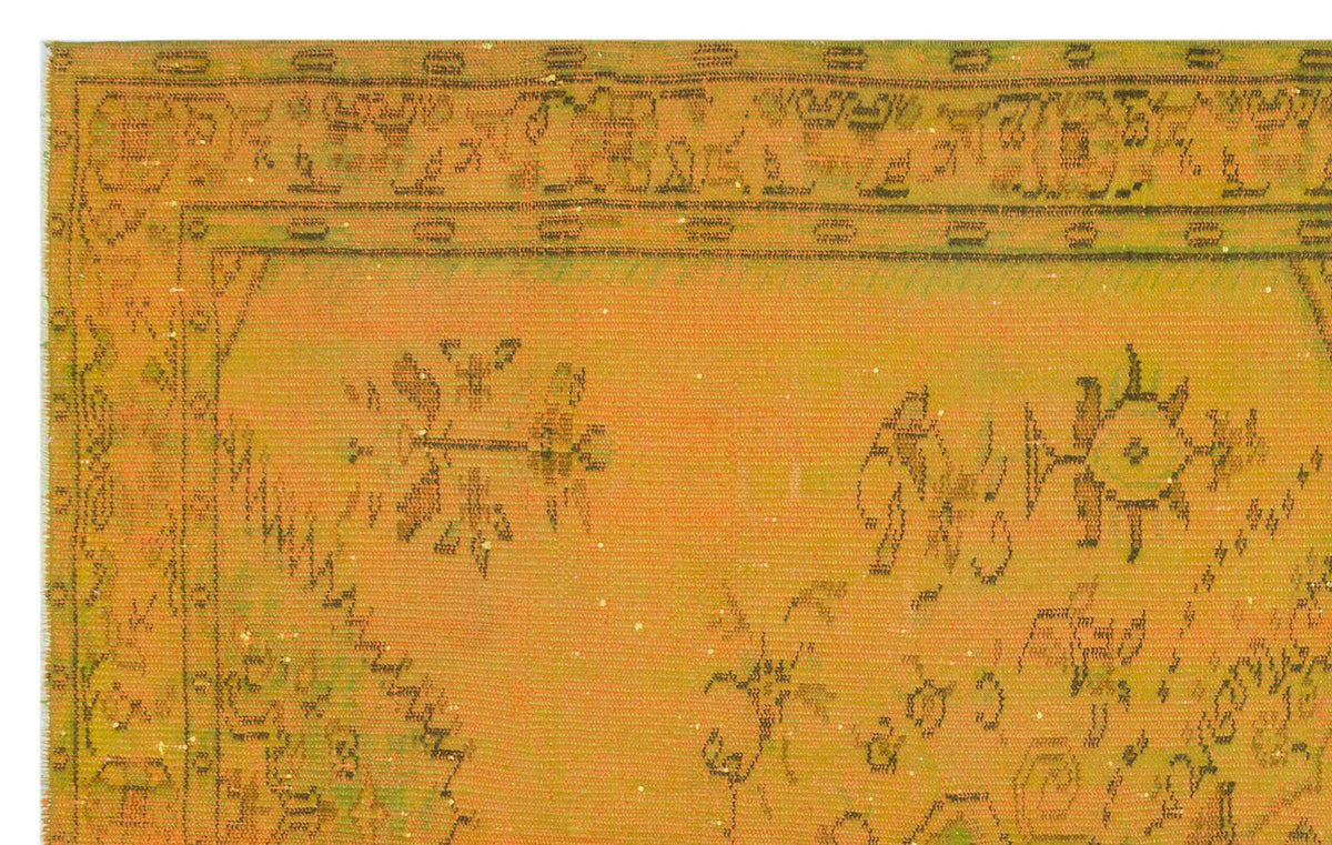 Mustard yellow vintage-style rug with a distressed dark green floral border and scattered abstract motifs.