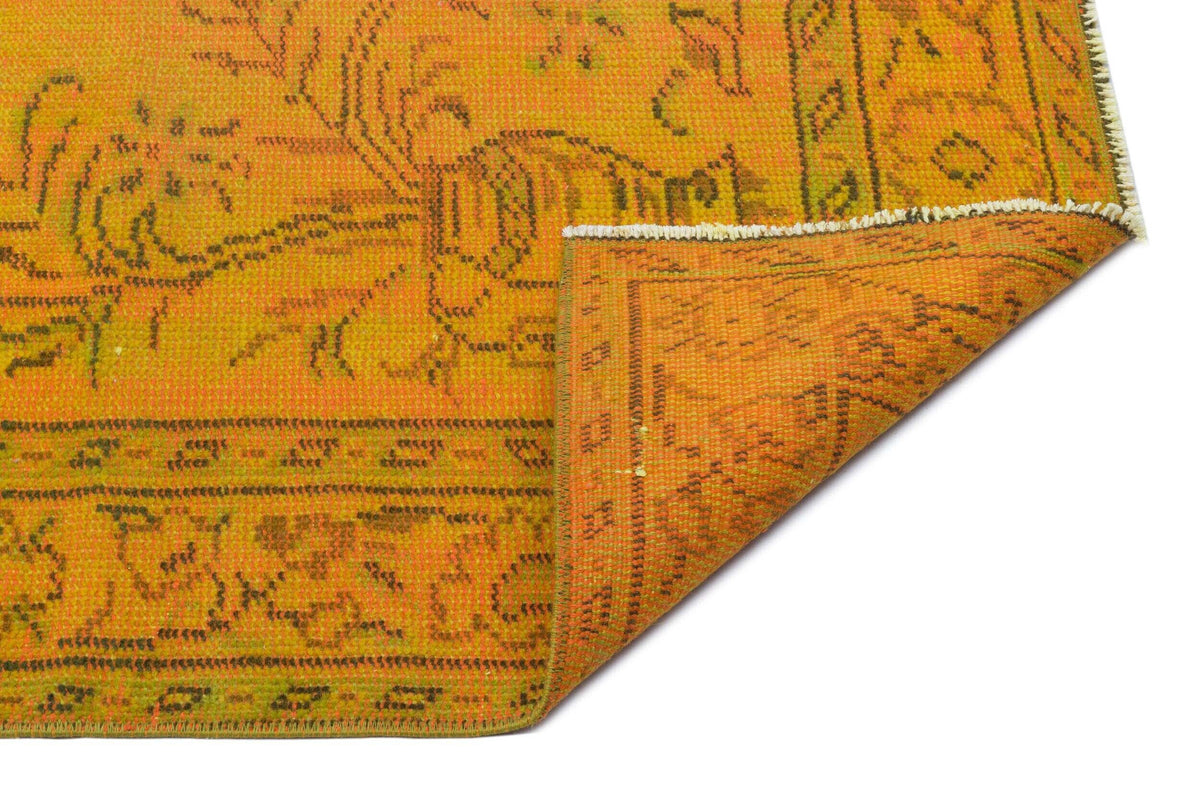 Bright orange and yellow vintage-style rug with a distressed floral medallion pattern and a folded corner.