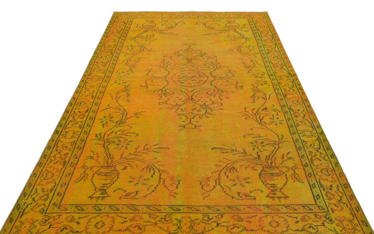 Mustard yellow vintage-style rug with a dark brown floral medallion and urn motif, isolated on a white background.