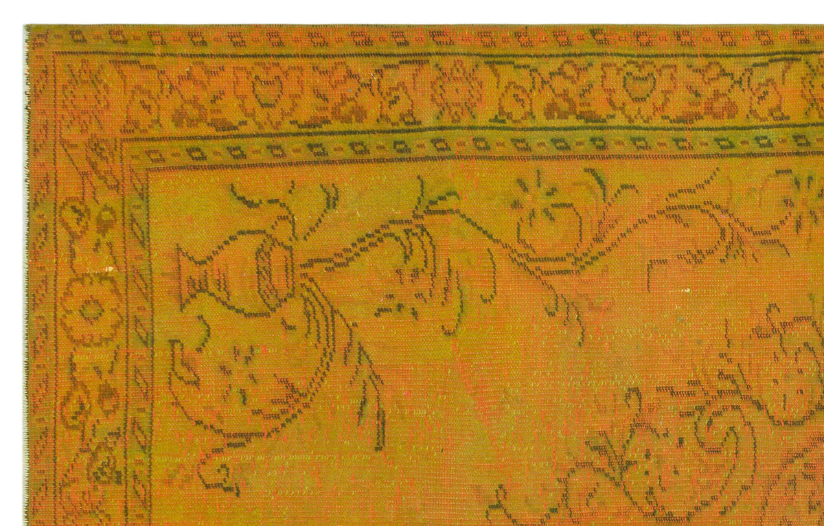 Mustard yellow rug with a dark green floral and urn motif, featuring a decorative geometric border.