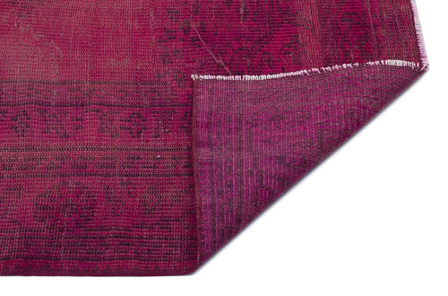 Load image 1 in gallery view. Magenta distressed rug with a dark, faded geometric pattern and a folded corner showing the underside texture.