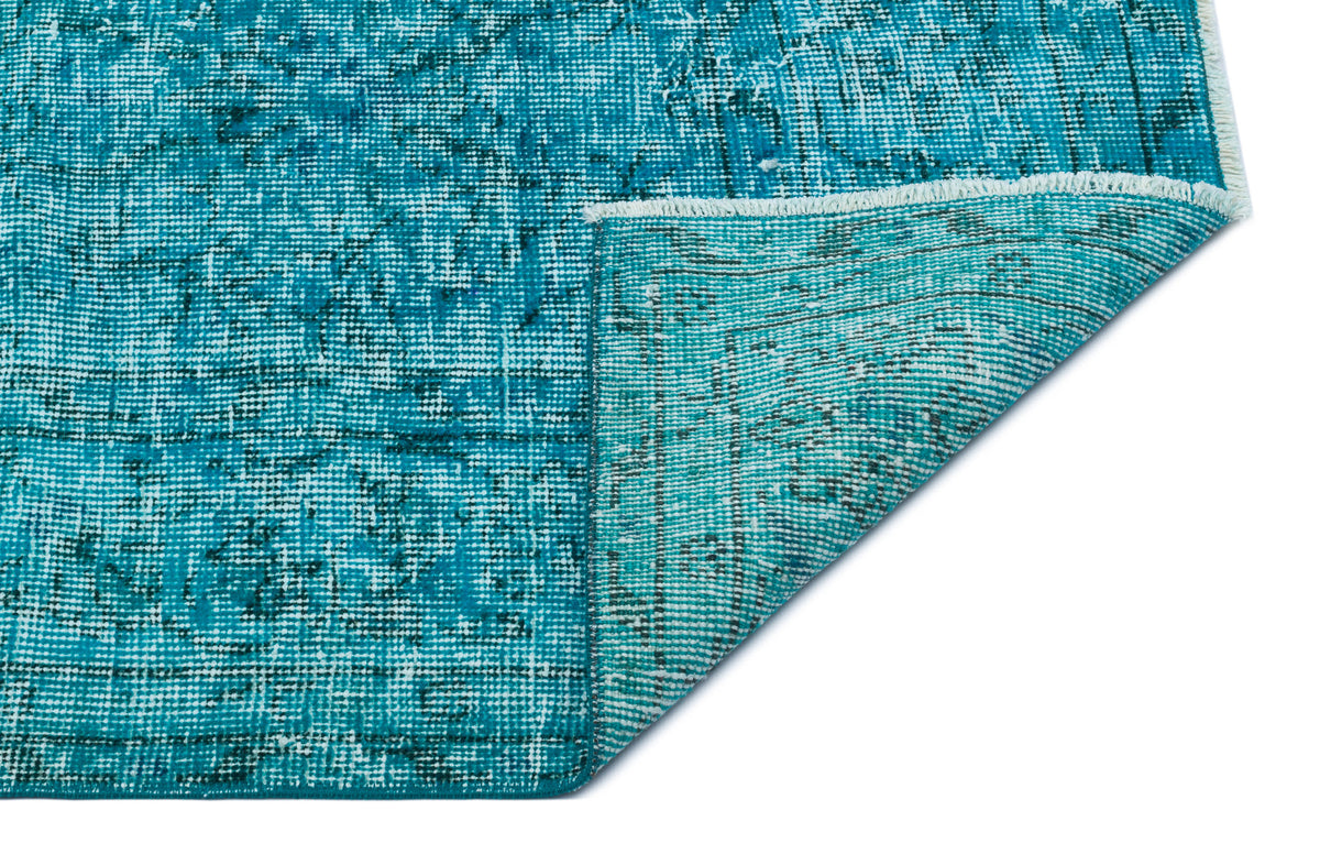 Teal and black distressed traditional rug with a folded corner showing the woven backing on a white background.