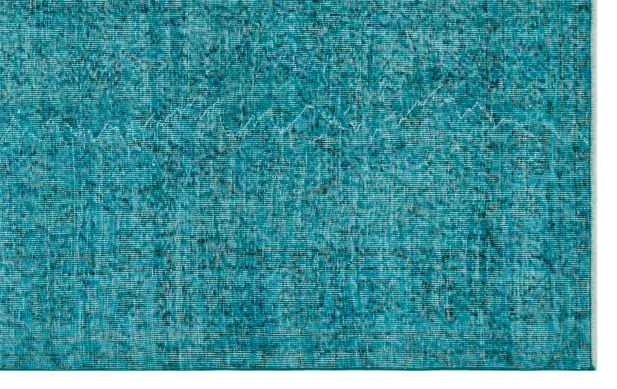 Teal distressed rug with a faded, intricate traditional pattern and a visible woven texture.
