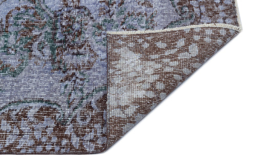 Load image 1 in gallery view. Distressed lavender and brown floral rug with a folded corner revealing the woven backing on a white background.