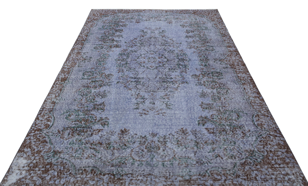 Distressed periwinkle blue rug with a brown and teal traditional floral medallion pattern on a white background.