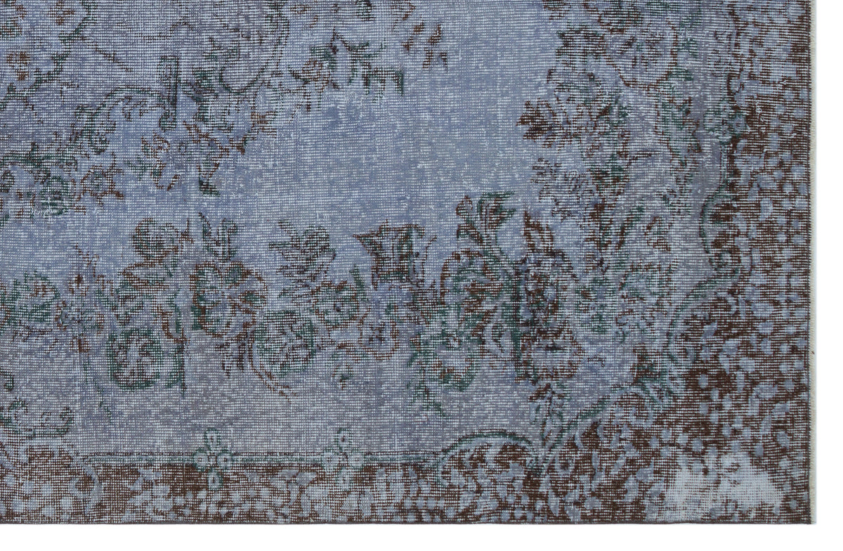 Distressed blue and brown rug with a faded floral medallion pattern on a white background.