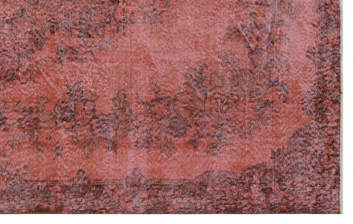 Terracotta and dark brown distressed rug with a faded floral medallion pattern.