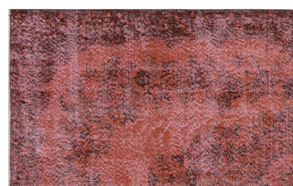 Distressed terracotta and dark brown rug with a faded floral medallion pattern.