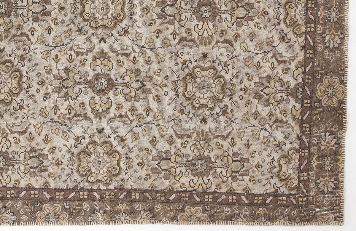 Beige and brown traditional rug with a repeating floral medallion pattern and a wide, detailed border.