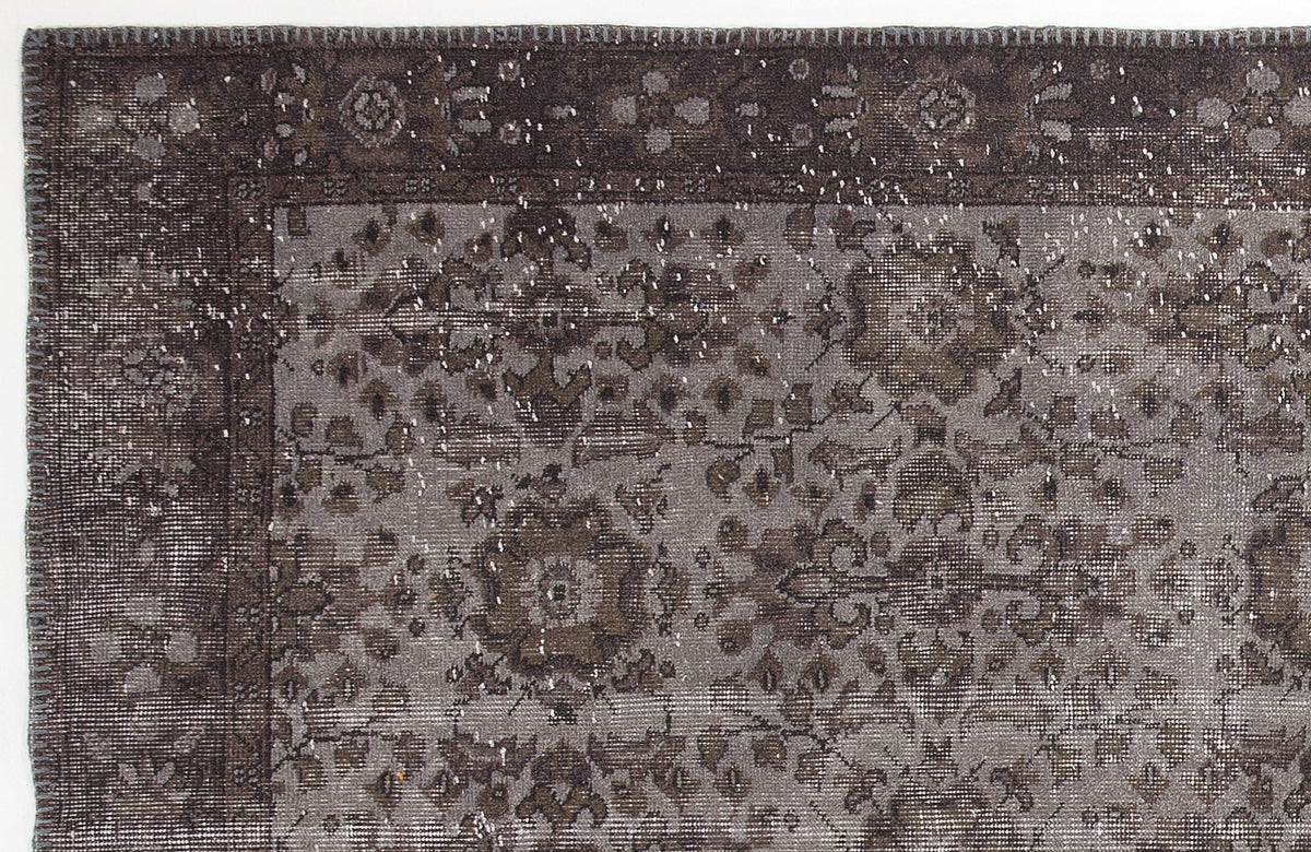 Dark charcoal and grey distressed rug with a traditional floral medallion pattern and a stitched border.