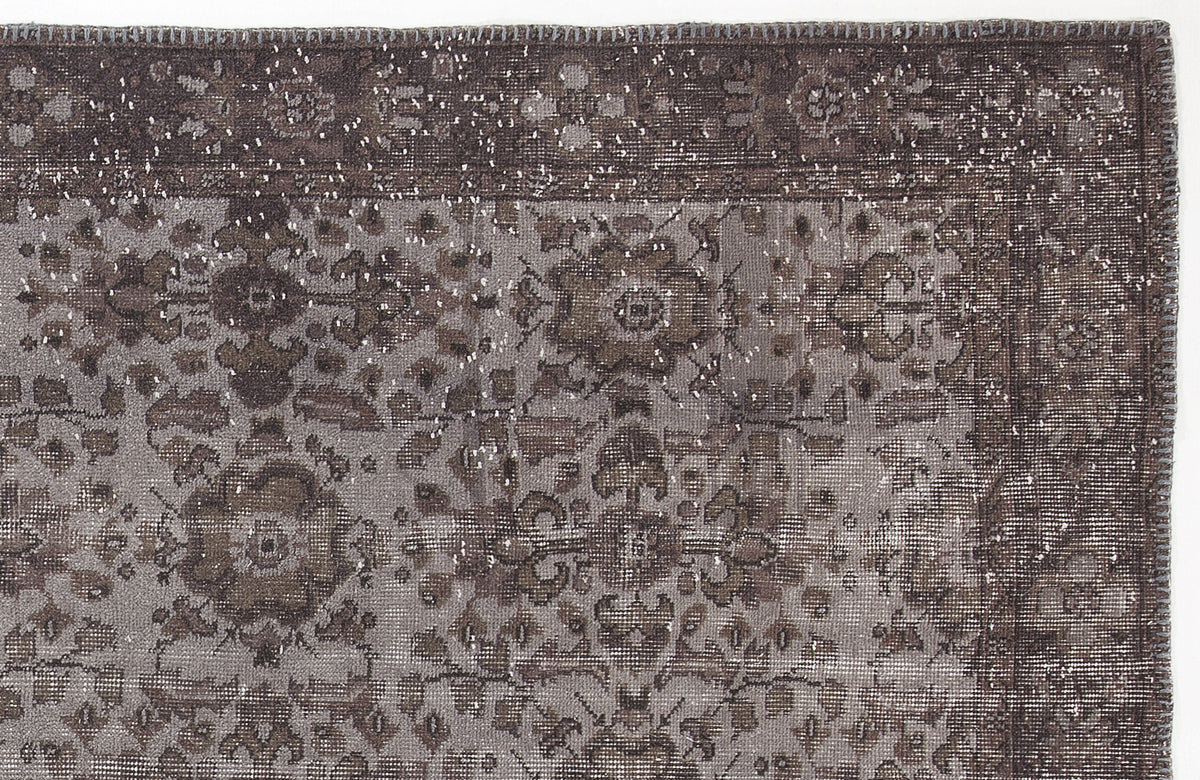 Dark brown and grey distressed rug with a traditional floral medallion pattern and a bordered edge.