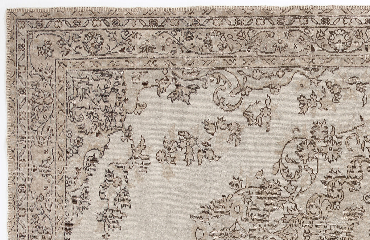 Beige and taupe rug with a traditional floral medallion border and distressed botanical pattern.