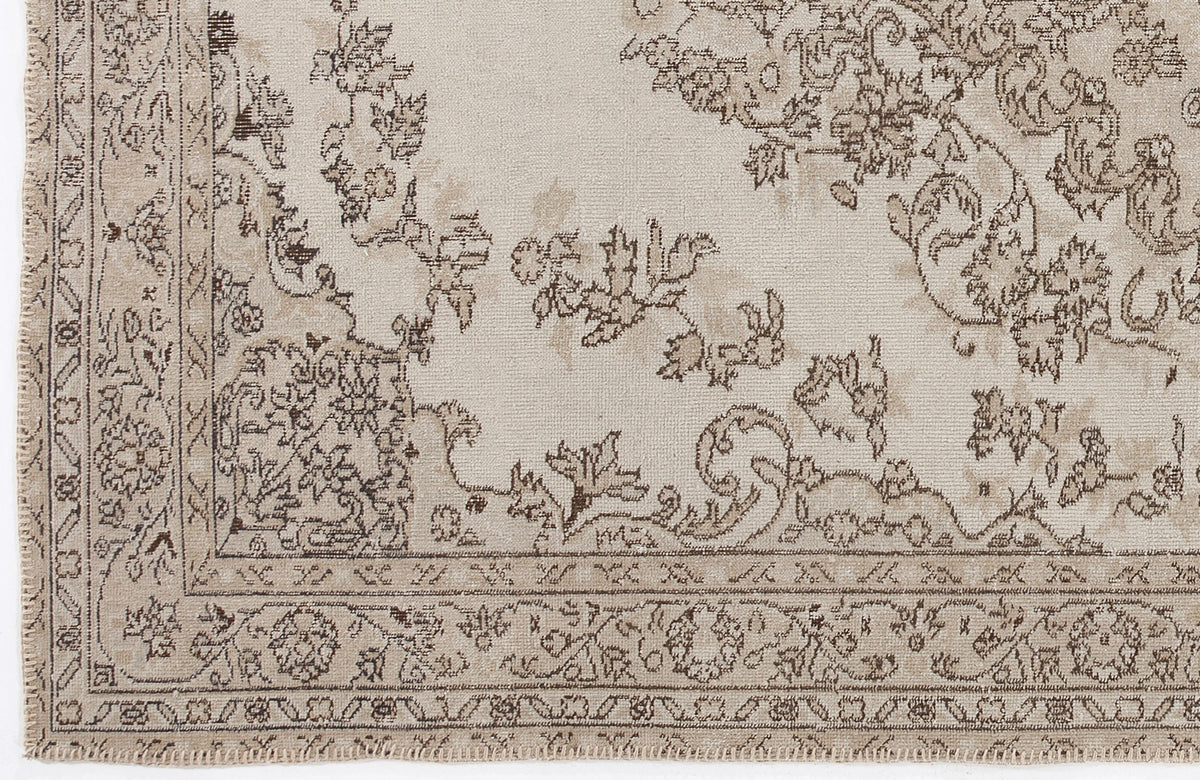 Beige and taupe traditional rug with a distressed floral medallion pattern and a detailed geometric border.