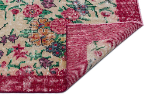 Load image 1 in gallery view. Beige rug with a multi-colored floral pattern and a wide magenta border, shown with a corner folded over.
