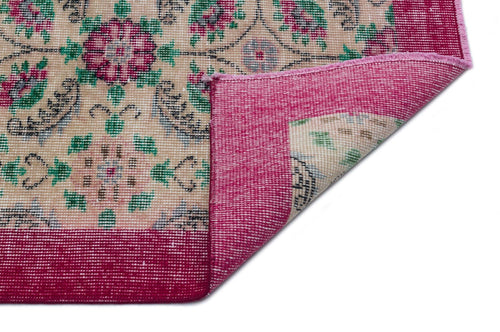 Load image 1 in gallery view. Beige rug with a floral medallion pattern in magenta and green, featuring a wide magenta border and a folded corner.