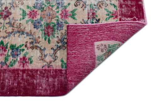 Load image 1 in gallery view. Beige rug with a floral pattern in pink, green, and blue, featuring a folded corner revealing a solid magenta border.