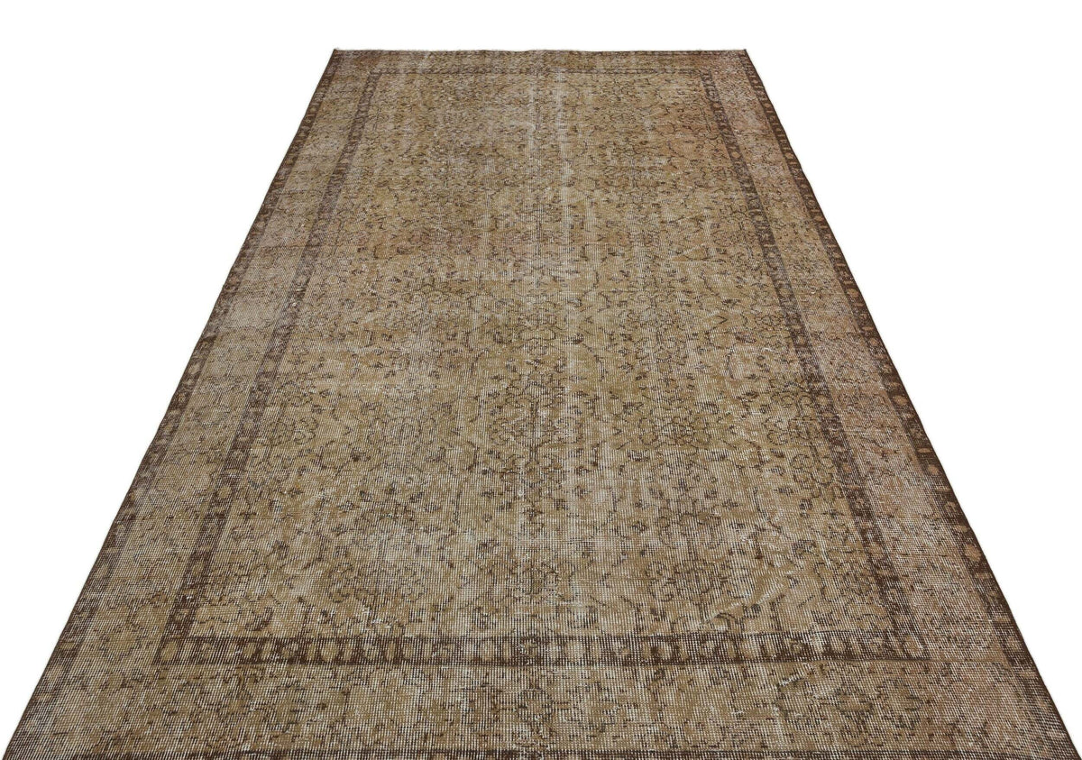 Distressed brown and tan vintage-style rug with a faded floral medallion pattern and a wide decorative border.