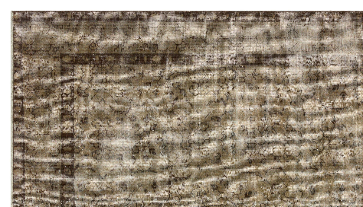 Brown and beige vintage-style rug with a distressed traditional medallion pattern and a geometric border.