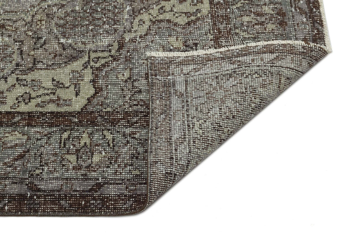 Distressed brown and grey traditional rug with a folded corner revealing the woven backing on a white background.