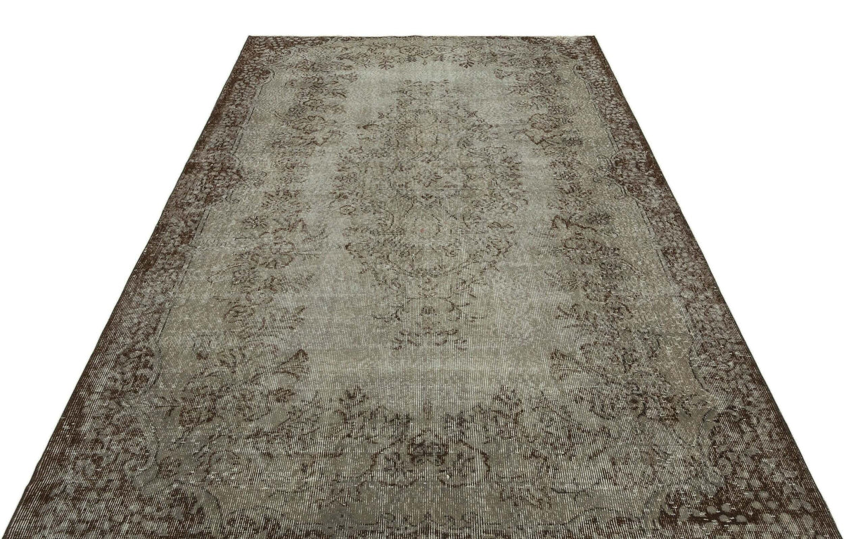 Distressed grey and brown rug with a traditional central medallion and ornate floral border.