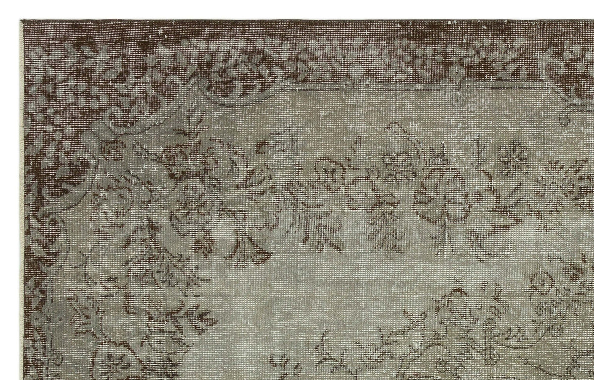 Distressed brown and taupe rug with a faded floral medallion pattern and a wide decorative border.