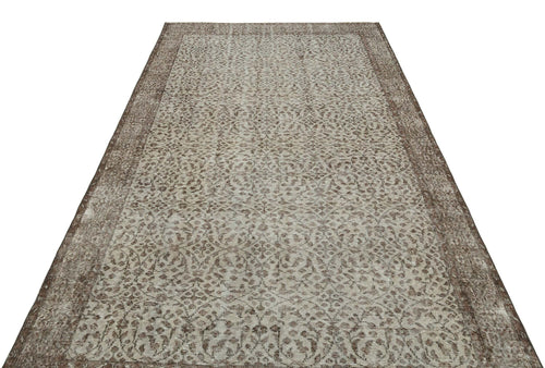 Load image 1 in gallery view. Brown and beige vintage-style rug with an intricate distressed floral pattern and a wide decorative border.