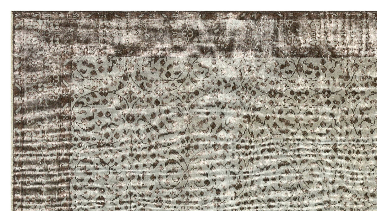 Brown and beige vintage-style rug with a distressed floral medallion pattern and a wide decorative border.