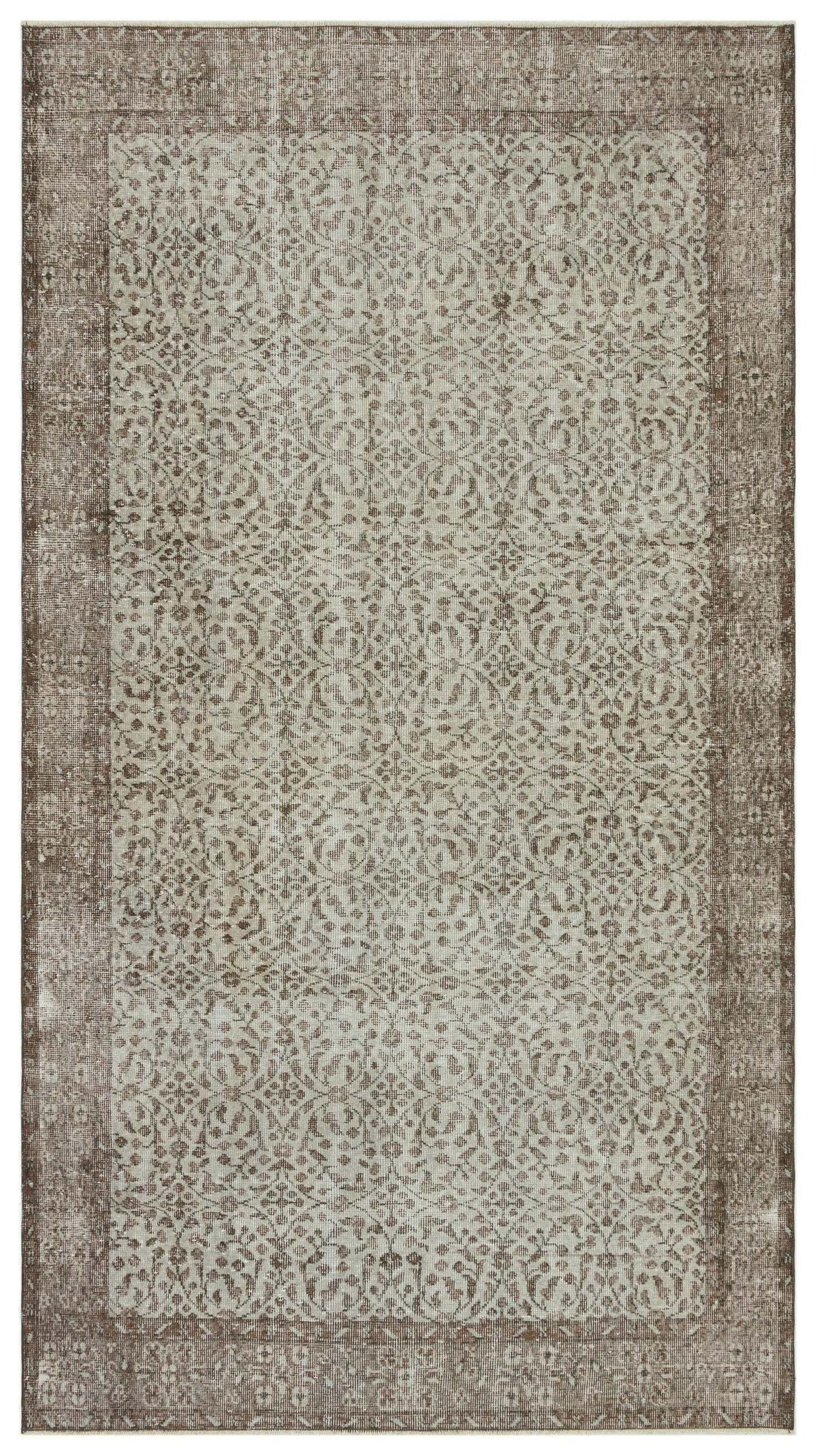 Taupe and cream distressed rug with a traditional repeating floral medallion pattern and a wide border.