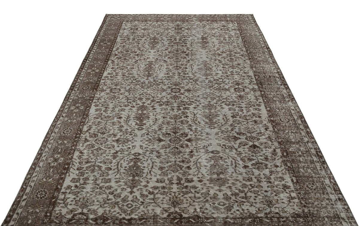 Brown and grey distressed traditional rug with an intricate floral medallion pattern and a wide border.